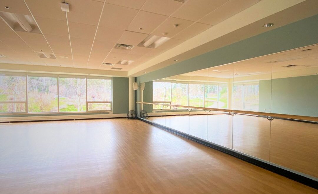 A brightly lit studio featuring a large mirror spanning an entire wall.