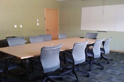 A boardroom with 9 chairs around a long table.