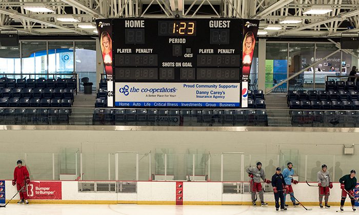 Arena scoreboard advertising display above the LCLC ice surface during hockey practice.